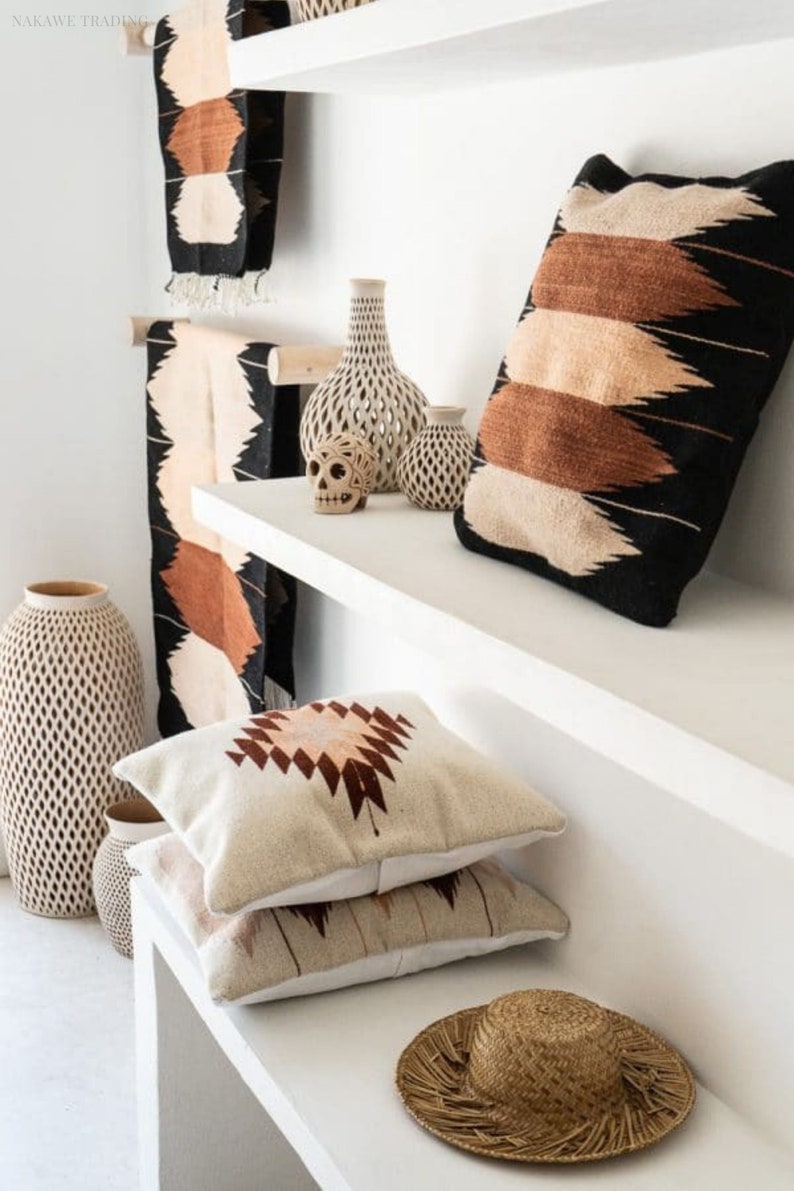 Puede incluir: Estantes blancos con una variedad de art&iacute;culos decorativos, incluyendo almohadas tejidas con patrones geom&eacute;tricos, jarrones de cer&aacute;mica y una calavera decorativa. Un sombrero de paja est&aacute; en el estante inferior.