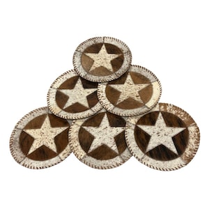 May include: A set of six round coasters with a star design. Each coaster features a white star on a brown and white cowhide background, with a stitched edge. The coasters are arranged in a triangular pattern.