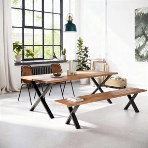 May include: A wooden dining table and bench set with black metal cross legs. The table has a natural wood finish, and the bench is placed in front of it. Two chairs with brown leather seats are visible. The room has a large window and plants.