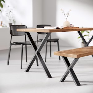 May include: A wooden dining table with black X-shaped legs and a matching wooden bench. The table has a natural wood finish and the bench has a slightly darker wood finish.