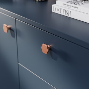 May include: Close-up of two drawers with hexagonal copper cabinet knobs on a dark blue cabinet.