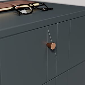 May include: A dark gray dresser with two drawers and a copper-colored knob. The dresser has a geometric pattern on the front.