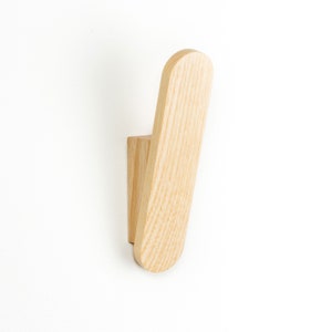 May include: A light wood wall hook with a rounded, slightly angled design.