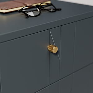 May include: A dark grey bedside table with a brass knob. The bedside table has a geometric pattern on the front.