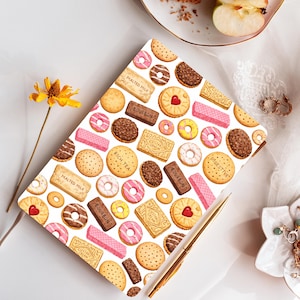 May include: A rectangular notebook featuring a repeating pattern of various biscuits and cookies, including pink-iced ring biscuits, chocolate-covered biscuits, and rectangular wafers labelled Malted Milk, Bourbon, Custard Cream, Rich Tea, and Digestive.