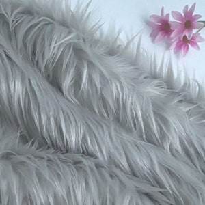 May include: A close-up of a soft, gray faux fur fabric. The fabric has a long pile and is very fluffy.