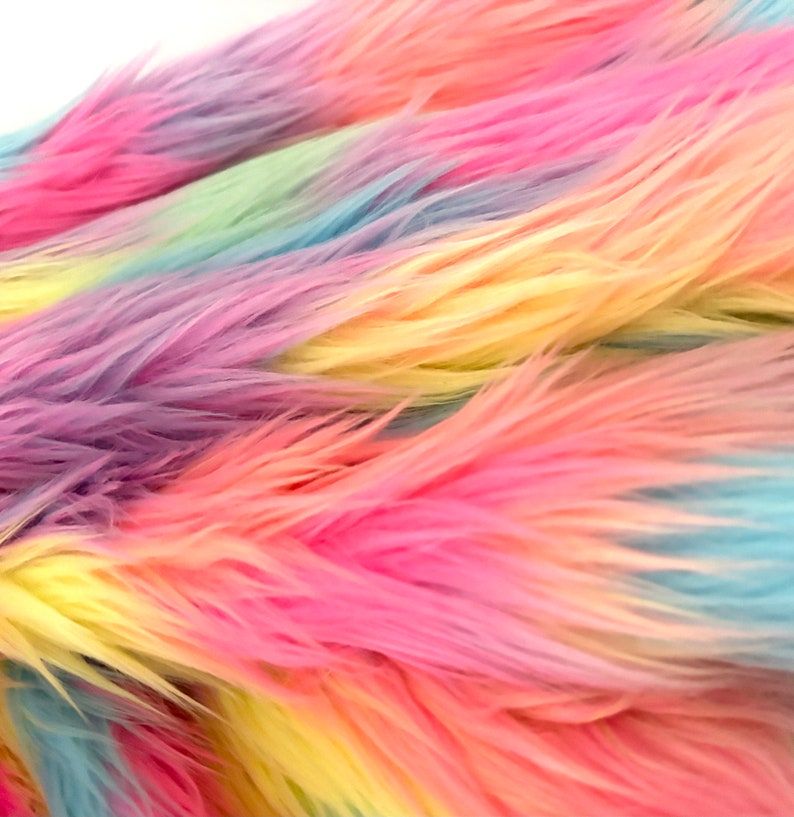 May include: Close-up of a rainbow-colored faux fur fabric. The fabric is soft and fluffy, with a gradient of colors from purple to blue to green to yellow to pink.