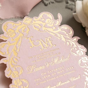 Könnte beinhalten: Eine rosafarbene Hochzeitseinladung mit goldenen Folienverzierungen und einem floralen Design. Die Einladung lautet: "Die Ehre Ihrer Anwesenheit wird bei der Trauung von Laura & Michael am Samstag, den 18. Mai 2024 um 15 Uhr erbeten."