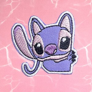 May include: Purple and white embroidered iron-on patch of Stitch from Lilo & Stitch, with a white outline and a pink nose.