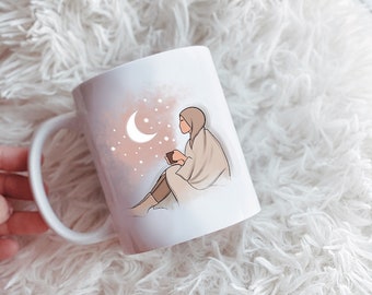 May include: White ceramic mug with a pink and white illustration of a person sitting with a cup, a crescent moon, and stars.