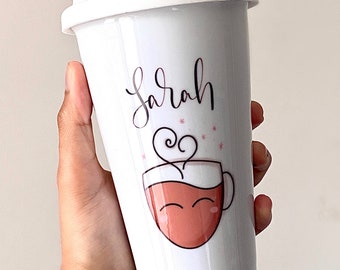May include: White ceramic travel mug with a pink and white design of a coffee cup with a smiling face and the name "Sarah" written in cursive.