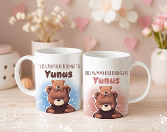 May include: Two white ceramic mugs with handles. Each mug features a brown bear illustration with a smaller bear on top. Text on the mugs reads "THIS DADDY BEAR BELONGS TO Yunus" and "THIS MUMMY BEAR BELONGS TO Yunus".