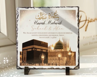 May include: A square slate plaque with rough, jagged edges featuring a printed image of the Kaaba and the Prophet's Mosque. The text reads Umrah Mubarak, Sohail & Alia, May Allah accept your journey and make it a means of spiritual growth, forgiveness, and barakah. Ameen, August 2026 | 1448AH.