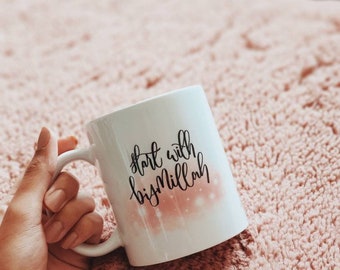 May include: White ceramic mug with a pink and white design. The mug has black calligraphy that reads "start with bismillah".