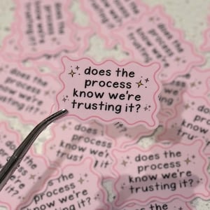 Op de afbeelding: Roze stickers met een golvende rand en de tekst "does the process know we're trusting it?" in zwart. De stickers hebben kleine sterren en glitterafbeeldingen. Een pincet houdt een sticker vast.