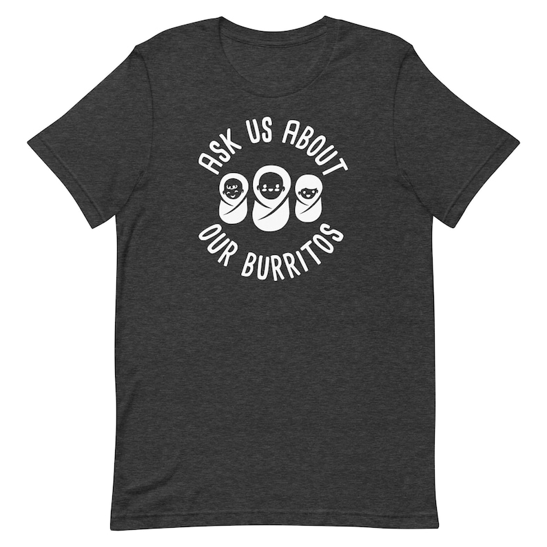 Puede incluir: Una camiseta gris oscuro con un dise&ntilde;o circular blanco que dice "Ask Us About Our Burritos" con tres caras de beb&eacute;s dentro del c&iacute;rculo.