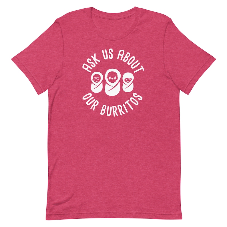 Puede incluir: Una camiseta rosa con un gr&aacute;fico blanco que dice "Ask us about our burritos" con tres caras de beb&eacute;s dentro de un c&iacute;rculo.