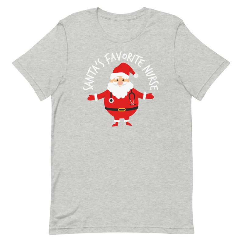 May include: A grey t-shirt with a white graphic of Santa Claus wearing a stethoscope and the text "Santa's Favourite Nurse".