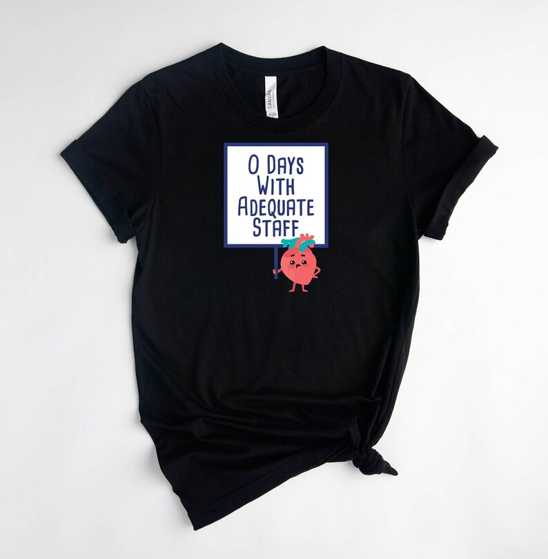 May include: Black t-shirt with a graphic of a cartoon heart holding a sign that says "0 Days With Adequate Staff".