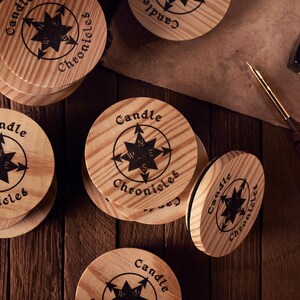 May include: Wooden coasters with the text "Candle Chronicles" and a compass rose design. The coasters are round, made of light-colored wood, and arranged on a dark wooden surface. An inkwell and quill are also present.