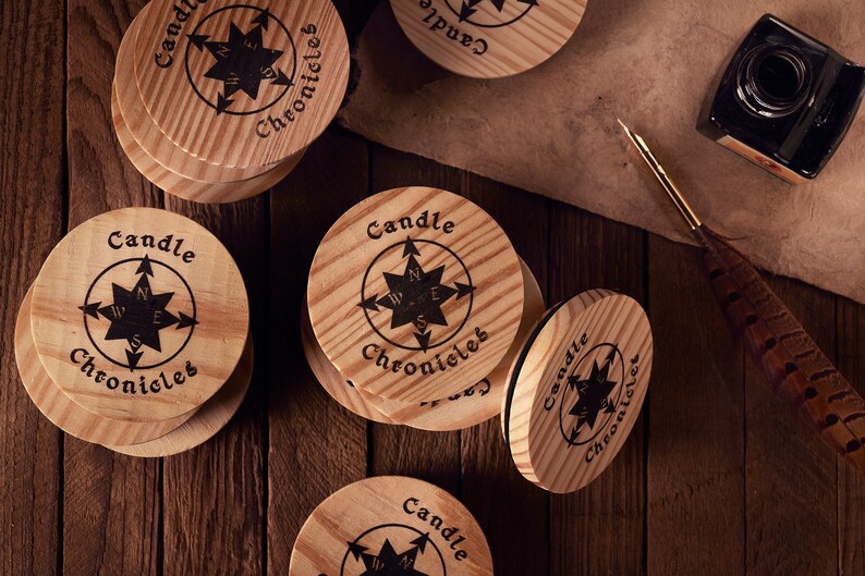 May include: Wooden coasters with the text "Candle Chronicles" and a compass rose design. The coasters are round, made of light-colored wood, and arranged on a dark wooden surface. An inkwell and quill are also present.