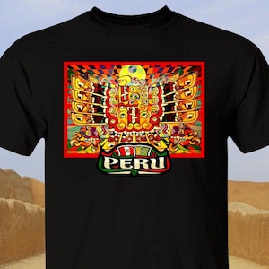 May include: Black t-shirt featuring a colorful graphic design with the word "PERU" at the bottom. The graphic is a stylized representation of a bird or deity, with intricate patterns in red, yellow, and green.