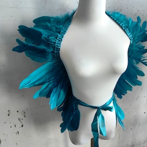 May include: Teal feather wings with a satin ribbon tie. The wings are attached to a white mannequin.