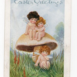 Peut inclure: Une carte de vœux de Pâques représentant trois fées assises sur un grand champignon. Les fées portent des ailes et ont les cheveux bouclés. La carte a un fond de ciel bleu avec des arbres verts au loin. Le texte "Easter Greetings" est écrit en cursive en haut de la carte. Le texte "Two's Company" est écrit en bas de la carte.