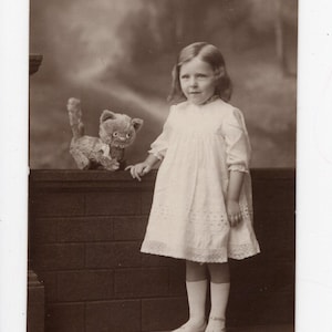 Antica cartolina fotografica di bambina e gatto giocattolo, gatto di peluche imbottito, bambino piccolo, ritratto di famiglia, bambini, bambino carino, foto in bianco e nero