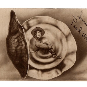 Puede incluir: Postal vintage en tonos sepia que muestra a una mujer sentada dentro de una estructura en forma de concha. La mujer lleva sombrero y botas. La postal está firmada "Sincerely Pearl White". La palabra "PATHE" es visible.
