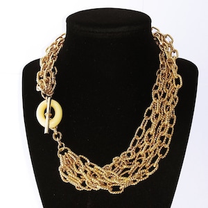May include: A gold multi-strand necklace with a white plastic toggle clasp.
