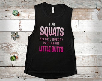 Puede incluir: Camiseta sin mangas negra con el texto "I DO SQUATS BECAUSE NOBODY RAPS ABOUT LITTLE BUTTS" en letras rosas y blancas. La camiseta sin mangas es sin mangas y tiene cuello redondo. La camiseta está sobre una superficie de madera blanca.