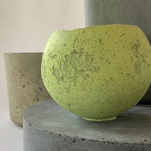 Peut inclure: Trois pots en béton, l'un est un pot rond vert, l'autre est un pot cylindrique gris haut et le dernier est un pot cylindrique beige plus court.