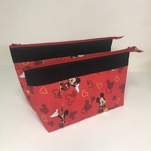 May include: Red zippered pouch with a black zipper and a Mickey Mouse print. The pouch has multiple compartments.