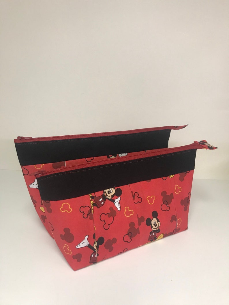 May include: Red zippered pouch with a black zipper and a Mickey Mouse print. The pouch has multiple compartments.