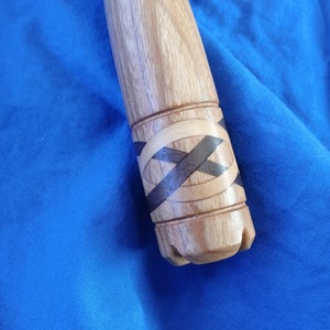May include: Close-up of a wooden handle with a decorative inlay of dark wood and light wood, creating a geometric pattern.
