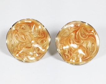 May include: A pair of gold-toned clip-on earrings with a swirling orange and white marbled design.