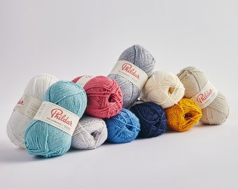 Peut inclure: Dix pelotes de laine de différentes couleurs, dont bleu, rouge, jaune, blanc et gris. La laine est étiquetée "Phildar" et est disposée en demi-cercle sur un fond blanc.