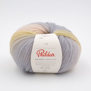 May include: A ball of light gray, yellow, and pink yarn with a white label that reads "Phil Nuage", "Legereté et Douceur", "72% Laine Mérinos", "28% Polyamide", "50g e 1,76 Oz", "148 m - 162 yds - 308 yds", and "CEREALE 100".