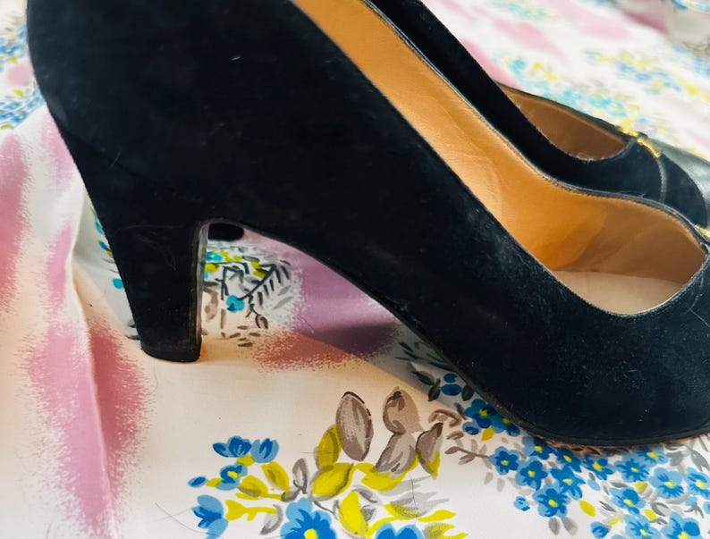 Puede incluir: Un par de zapatos de tac&oacute;n alto de ante negro con punta.