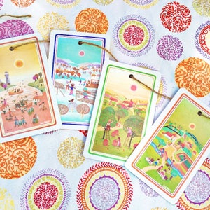 Puede incluir: Cinco tarjetas ilustradas coloridas con una cuerda que pasa por agujeros en las esquinas superiores. Las tarjetas representan escenas de personas trabajando en un campo, un pueblo, una granja y un bosque. Las tarjetas est&aacute;n sobre un fondo blanco con c&iacute;rculos de patrones coloridos.
