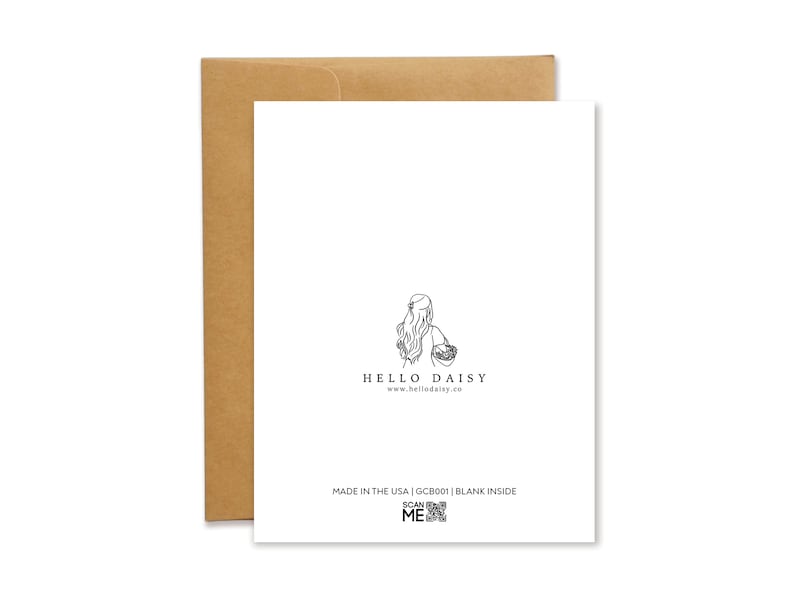 The back of the Hello Daisy greeting card. Features the Hello Daisy logo: a girl with long hair holding a basket of daisies. Below the logo is the text: Made in the USA, the SKU number, Blank inside, as well as a Scan Me QR code.