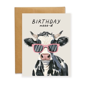 An adorable A2 sized greeting card featuring an illustration of a black and white cow with horns wearing a birthday hat and the text, Birthday Mood. Card has a beige background and comes with a brown kraft envelope.