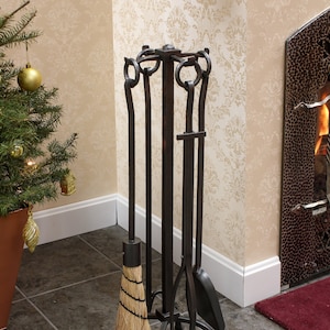 May include: A black metal fireplace tool set with a brush, poker, shovel, and tongs. The tools are mounted on a stand with a decorative design.