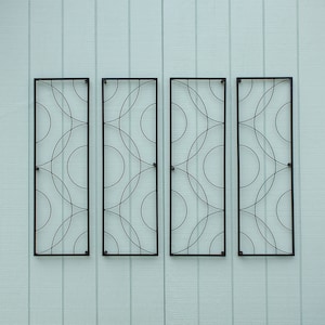 May include: Four rectangular black metal wall art panels with a repeating circular design. The panels are mounted on a light blue wooden wall. Each panel has a black frame and a pattern of overlapping circles.