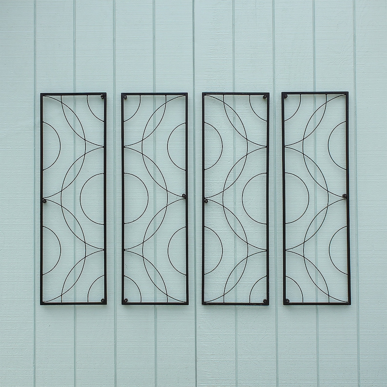 May include: Four rectangular black metal wall art panels with a repeating circular design. The panels are mounted on a light blue wooden wall. Each panel has a black frame and a pattern of overlapping circles.