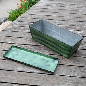May include: A green metal planter with a matching tray. The planter is rectangular and has a distressed finish. The tray is also rectangular and has a distressed finish.