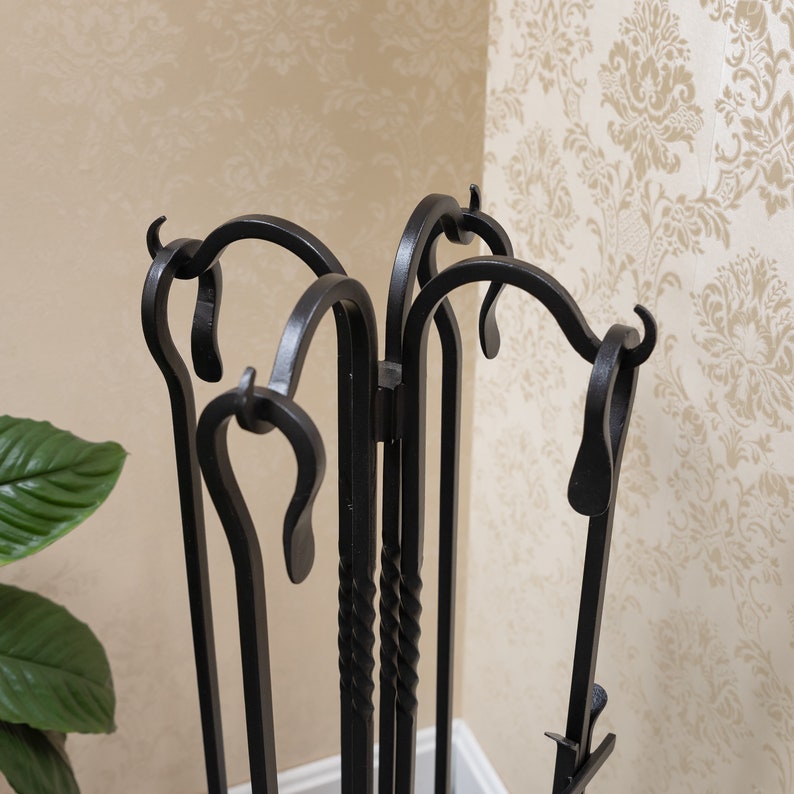 May include: A black wrought iron fireplace tool set. The set includes a poker, shovel, and brush, all with decorative curved handles. The tools are displayed in a matching stand with a scrolled design, perfect for keeping a hearth tidy and stylish.