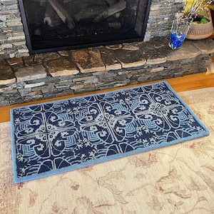 May include: A blue and white patterned rug with a geometric design. The rug is placed in front of a stone fireplace.