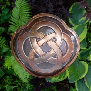 K&ouml;nnte beinhalten: Ein Wandkunstst&uuml;ck aus Kupfer mit einem keltischen Knotendesign in Form eines vierbl&auml;ttrigen Kleeblatts.